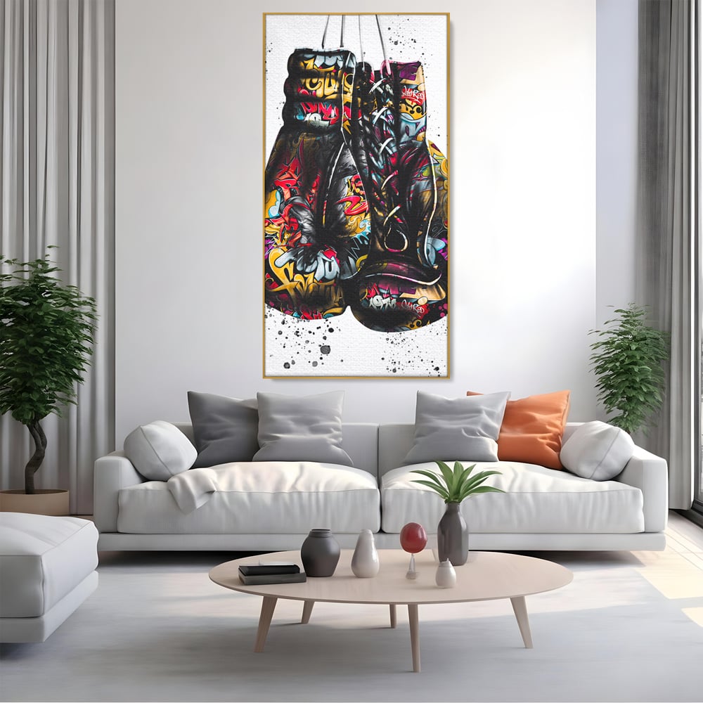 Tablou canvas cu tablou canvas cu manusi de box, in rama de aluminiu auriu, pe perete intr-un living